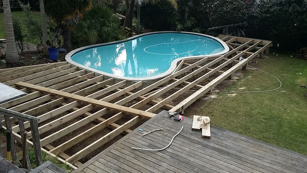 Deck subframe and joists being built around a pool